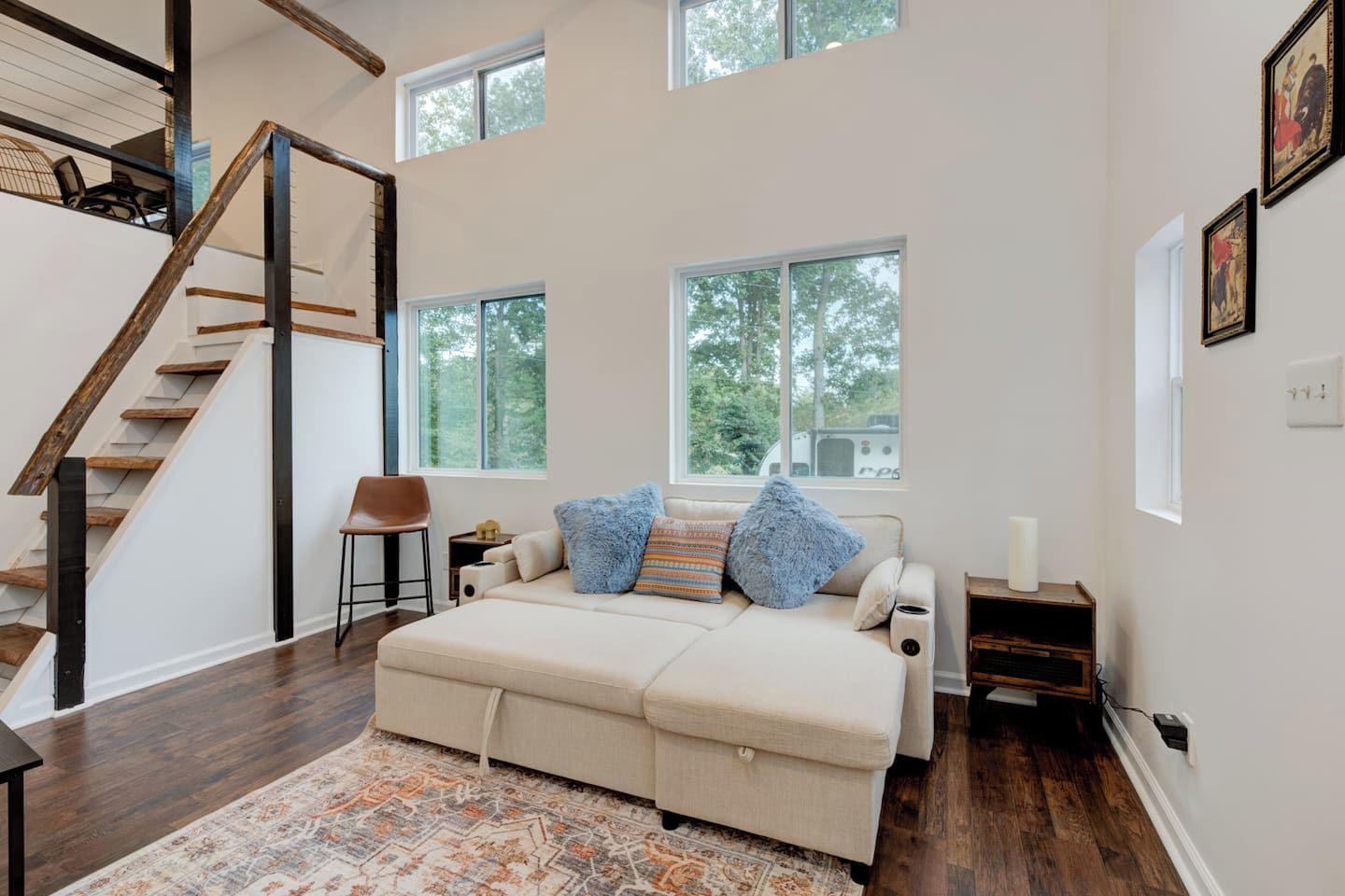 Una habitación amplia con una cama grande, una escalera de madera y varias ventanas.