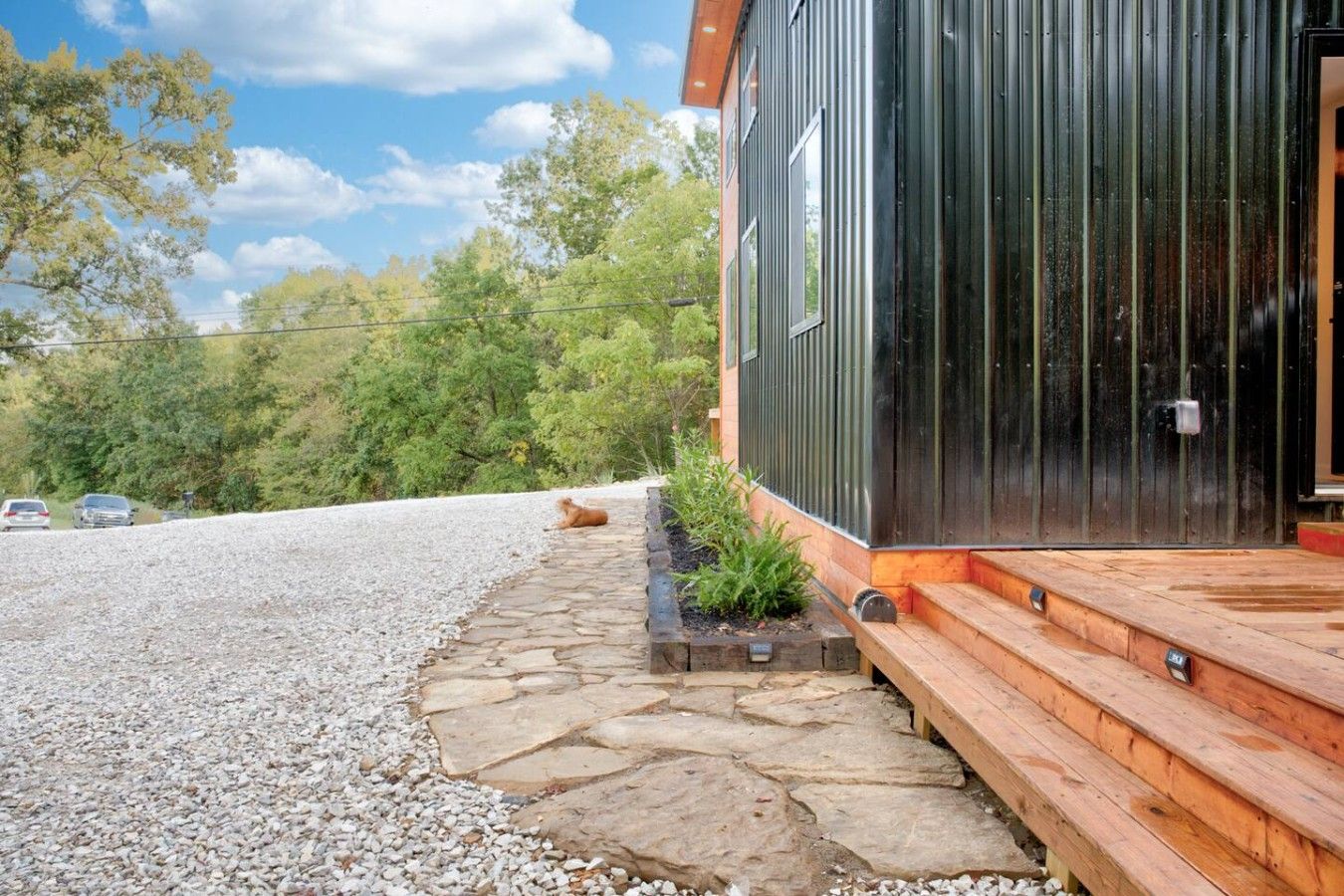 A modern building with a stone pathway leading to a wooden deck.