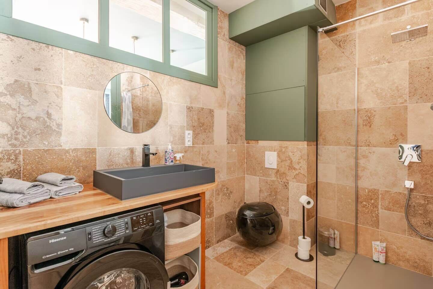 A modern bathroom with a sink, mirror, and a built-in washing machine.