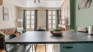 Une cuisine moderne avec un plan de travail en marbre, un coin repas doté d’un canapé capitonné et une vue dégagée grâce à de grandes fenêtres.