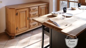 A kitchen with wooden cabinets, a large window, and a hanging light fixture.