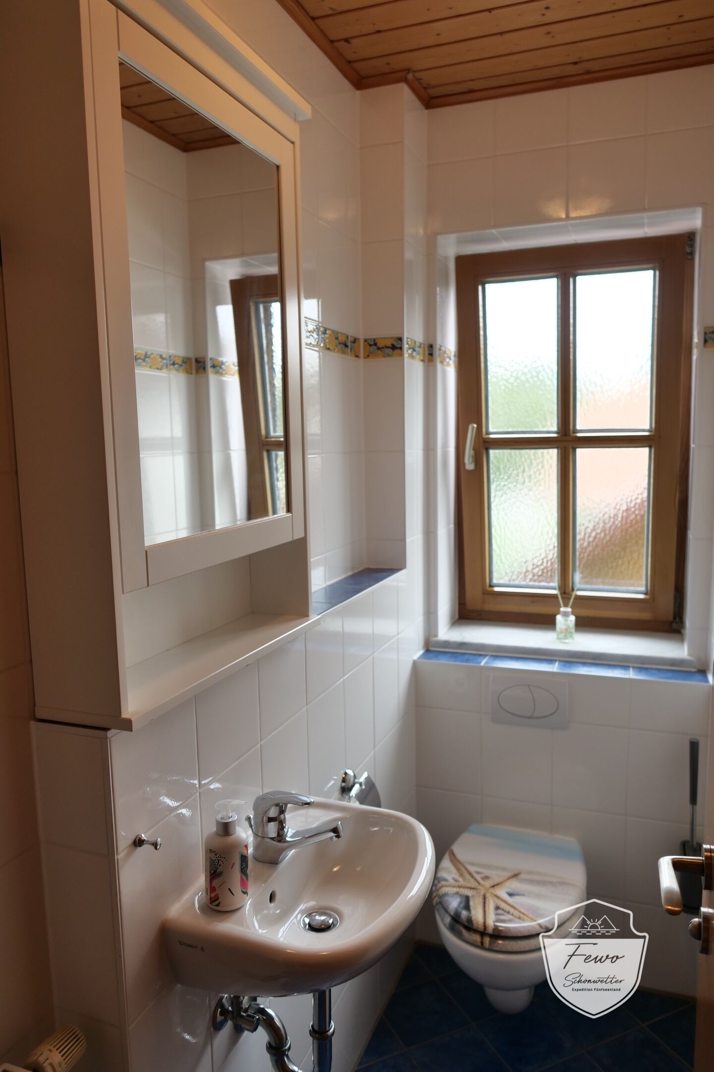 Un baño con lavabo, espejo, ventana y retrete.