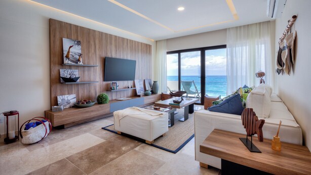 A modern living room with a large TV, comfortable seating, a view of the ocean, and a wooden accent wall. - Beatiful Penthouse with Private Pool & Breathtaking Ocean Views in Isla Mujeres (Isla Mujeres)