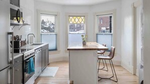 Una cocina moderna con una isla central, electrodomésticos integrados y amplios ventanales.