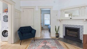 Amplia sala de estar con chimenea, un sofá azul y un tapete estampado.