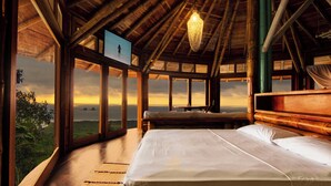 A room with a large bed, wooden beams, a hanging light fixture, and a view of the ocean. - Cabañas Cochapunko I Espectacular vista 360 (Salango)