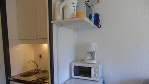 Una kitchenette compacta con un lavamanos, un microondas y un refrigerador pequeño.