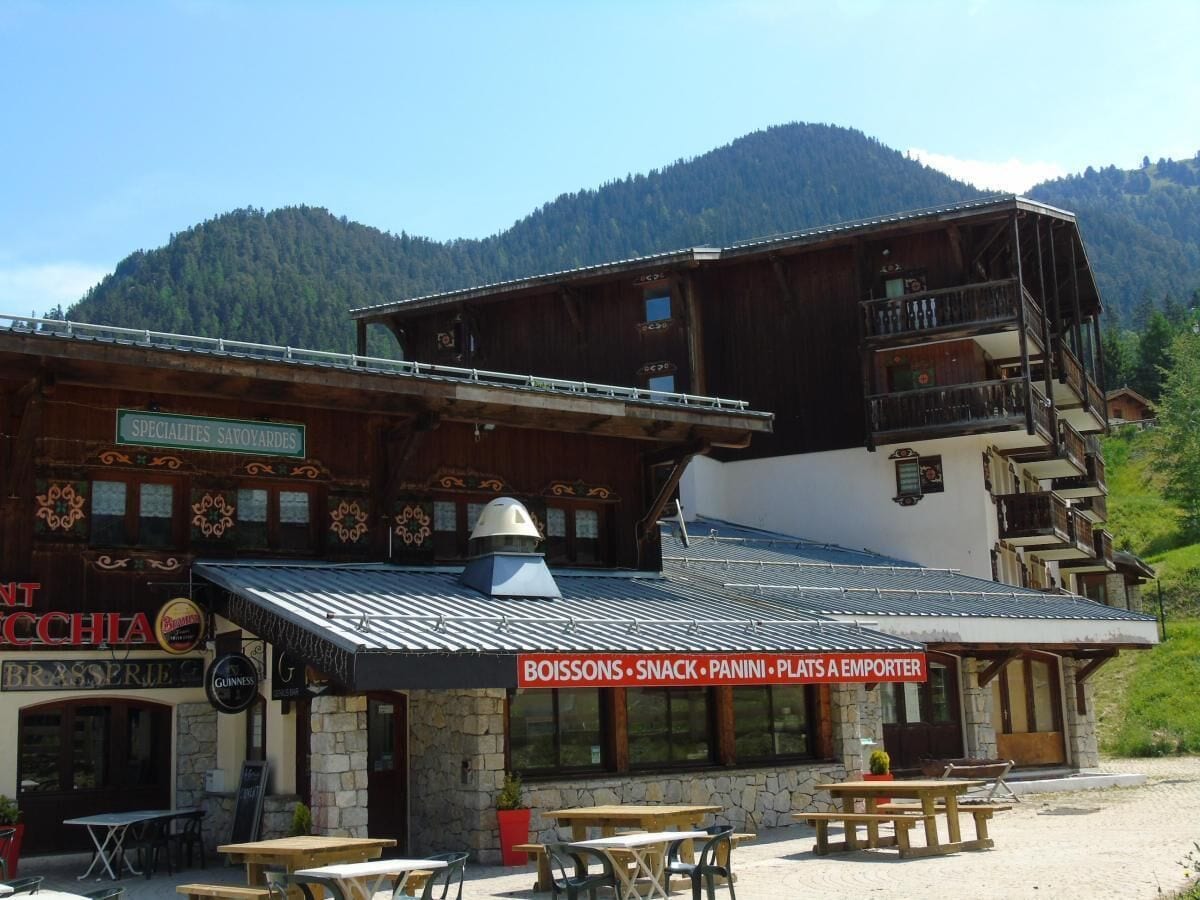 A mountain lodge with a signboard advertising specialties, a brasserie, and a restaurant offering snacks, panini, and a play area for children.