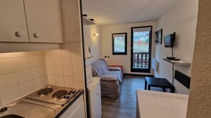 Una cocina compacta con estufa, un pequeño comedor y un sofá al fondo.