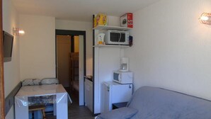 Un espacio habitable compacto con kitchenette, comedor y sofá.