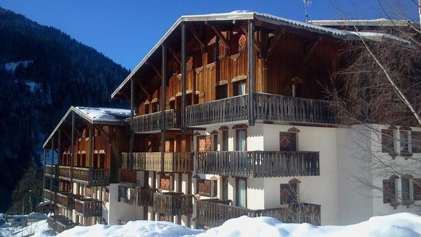 Una cabaña de madera con varios balcones y un paisaje cubierto de nieve.