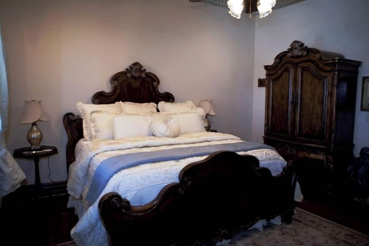 Une chambre à coucher avec un grand lit, une armoire en bois et une table de chevet avec une lampe.