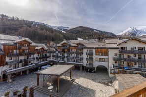 Ein Skigebiet mit Holzhäusern, Außenbestuhlung und einem Bergpanorama.