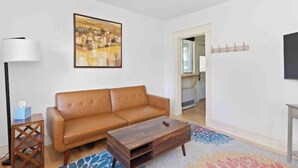 Un salon avec un canapé en cuir marron, une table basse en bois, un lampadaire et un tapis coloré.