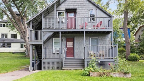 Une maison à deux étages avec un porche à l’avant et une petite terrasse.