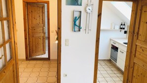 Un pasillo con una puerta de madera que da a una habitación con piso de baldosas hexagonales.