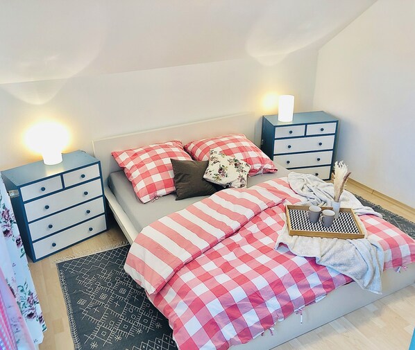 Une chambre à coucher comprenant un lit, deux tables de chevet, une commode et une lampe de chevet.