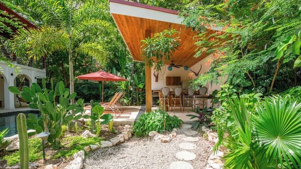 A garden with a pool, outdoor seating, and a wooden pergola. - Jungle Villa w/ Lush Gardens walk 2 Pelada Beach (Nosara)