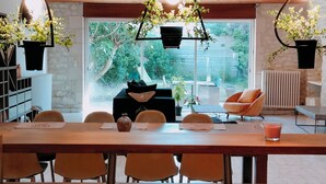 Une cuisine moderne avec des poutres en bois, des luminaires suspendus et une grande table à manger.