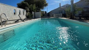 Une piscine aux eaux cristallines, entourée d’une clôture blanche, avec un palmier en arrière-plan.