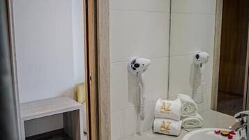A modern bathroom with a white sink, two hair dryers, and neatly folded towels on the counter.