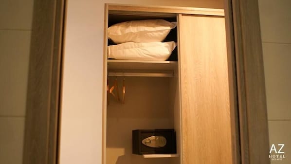 A wooden wardrobe with a hanging rack and a small safe.