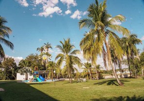 Un resort tropicale con palme, un'area giochi e una piscina.