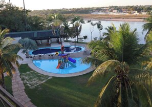 A pool area with a slide and a bridge over water. - Araguaia Hotel (Barra do Garcas)