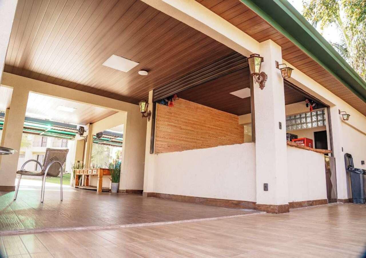 A spacious indoor area with a wooden ceiling, a bench, and potted plants.