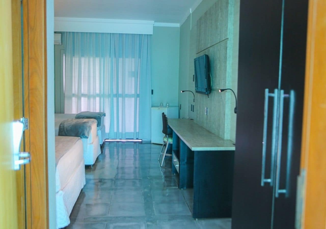 Ein Hotelzimmer mit einem Bett, einem Schreibtisch, einem Stuhl, einem Fernseher und einem Kleiderschrank.