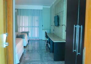 Ein Hotelzimmer mit einem Bett, einem Schreibtisch, einem Stuhl, einem Fernseher und einem Kleiderschrank.