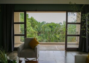 A room with a large window, a chair with a cushion, and a view of greenery outside. - Araguaia Hotel (Barra do Garcas)