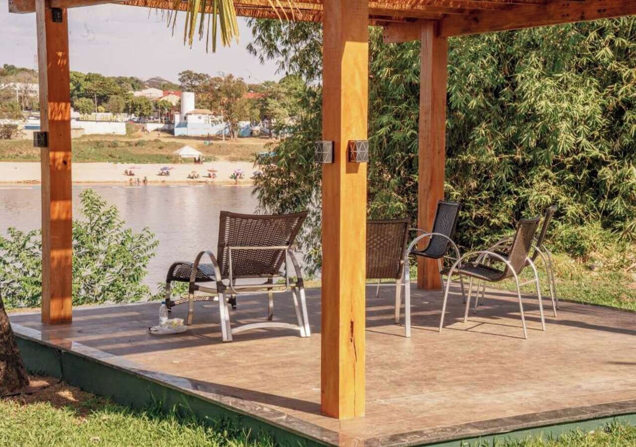 En utomhusplats med sittplatser, bestående av stolar och ett bord, med utsikt över en vattenyta och grönområden.