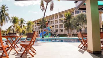 Un área junto a la piscina con sillones de descanso y una zona de juegos para niños.