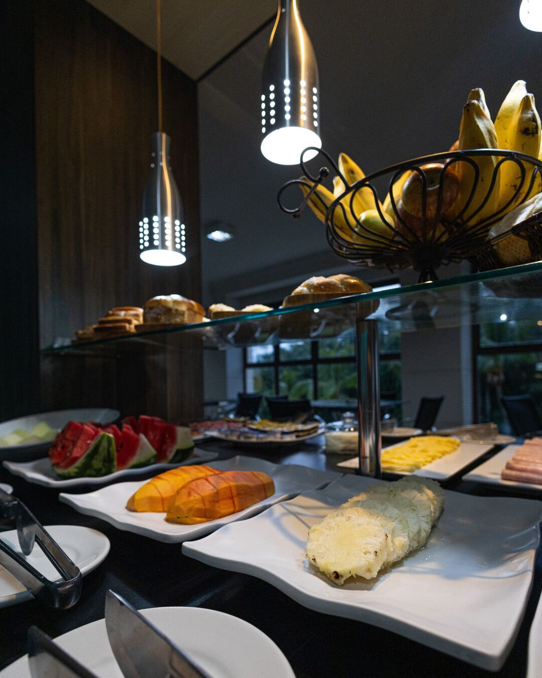 Ein Buffet mit verschiedenen Speisen, darunter Obst, Gebäck und ein Brötchen.