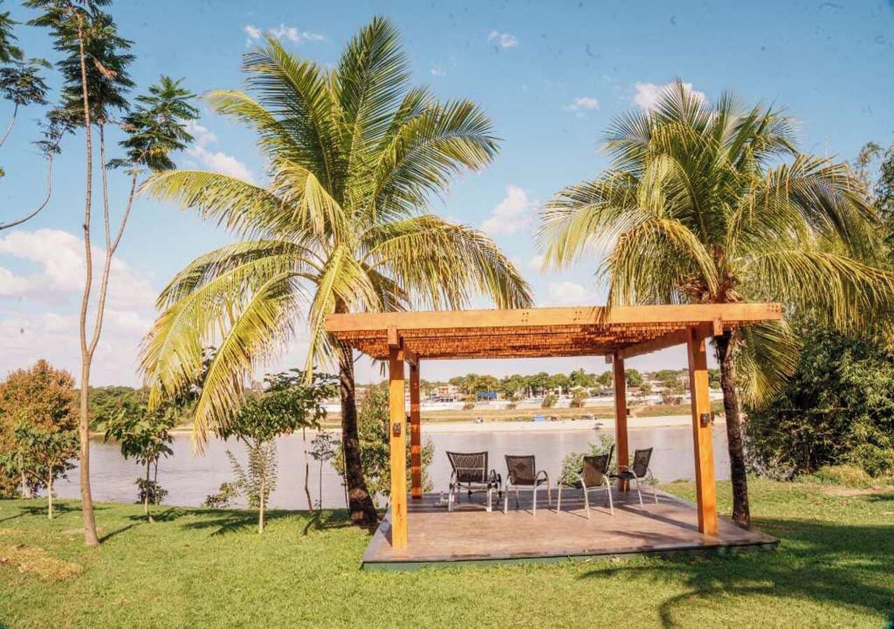 Een overdekt terras met stoelen, palmbomen en uitzicht op een waterpartij.