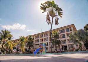 A hotel with multiple floors, a pool area with lounge chairs, and palm trees. - Araguaia Hotel (Barra do Garcas)