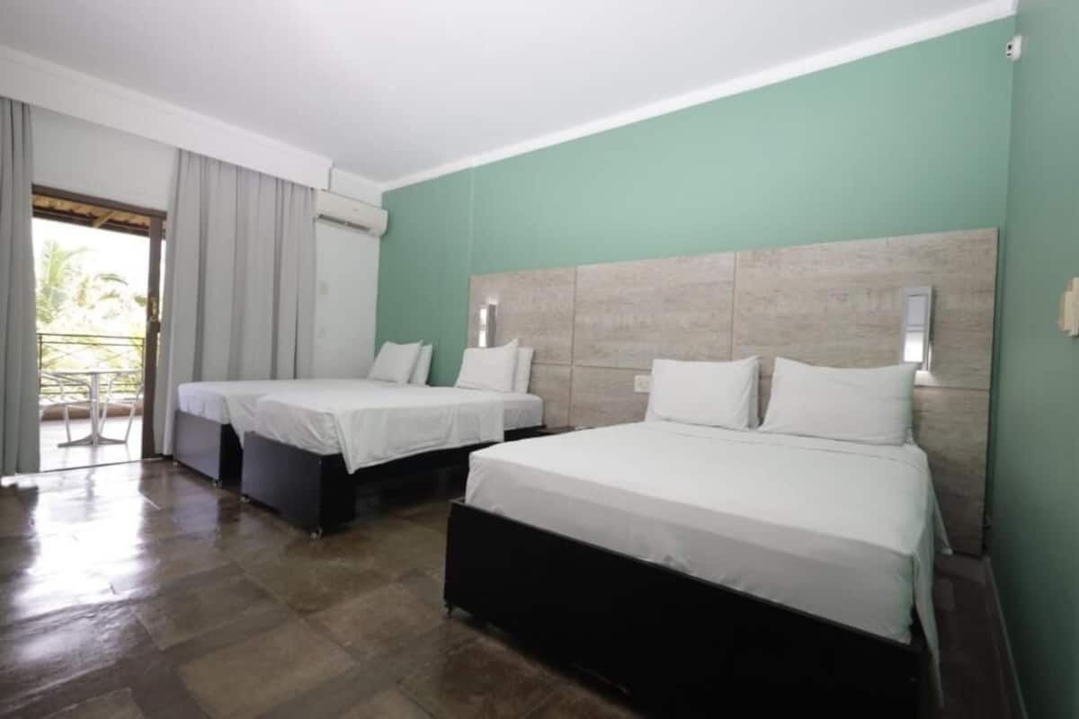 A hotel room with two single beds, a large window with curtains, and a balcony.