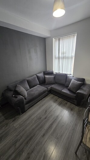 A modern living room with a sectional sofa, a ceiling light, and a window with blinds. - Entrepreneur Stays - 8 Guest Lovely home in Liverpool *NO GUEST FEE (Liverpool)
