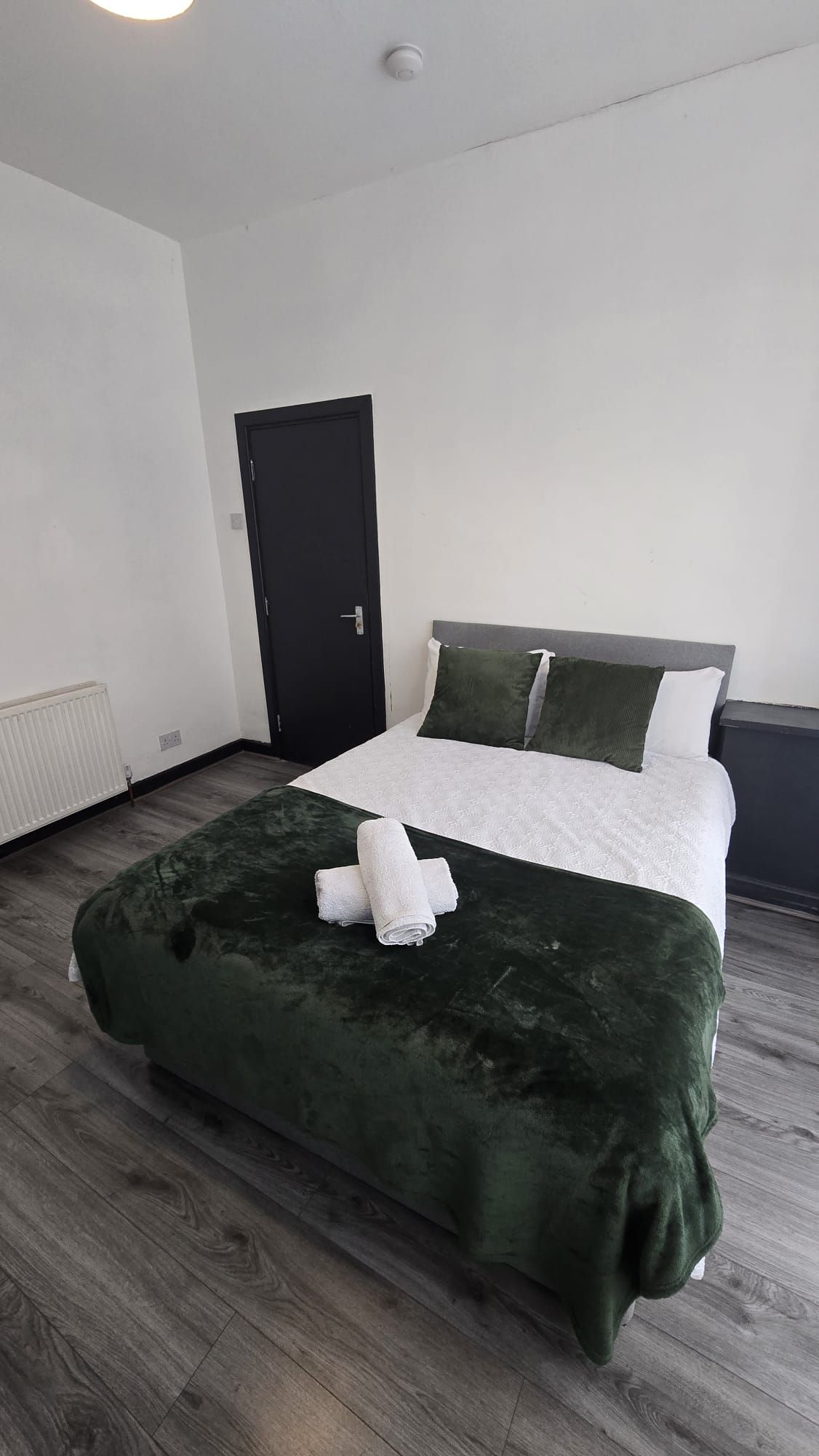 A hotel room with a bed, a door, and a radiator.