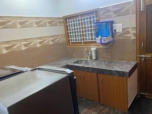 A small kitchen with a sink, wooden cabinets, and a window with a metal grid.