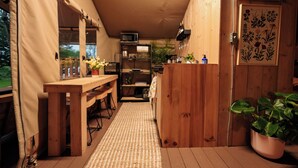 Een kleine keuken met een houten tafel, een magnetron en een spoelbak.