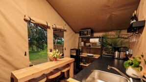 Een compacte keuken met een houten bar, een spoelbak, een magnetron en een koffieapparaat.