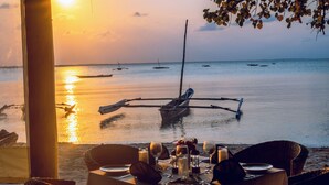 Mesa lista para comer con vista a barcos en agua tranquila durante el atardecer.