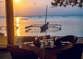 Mesa lista para comer con vista a barcos en agua tranquila durante el atardecer.