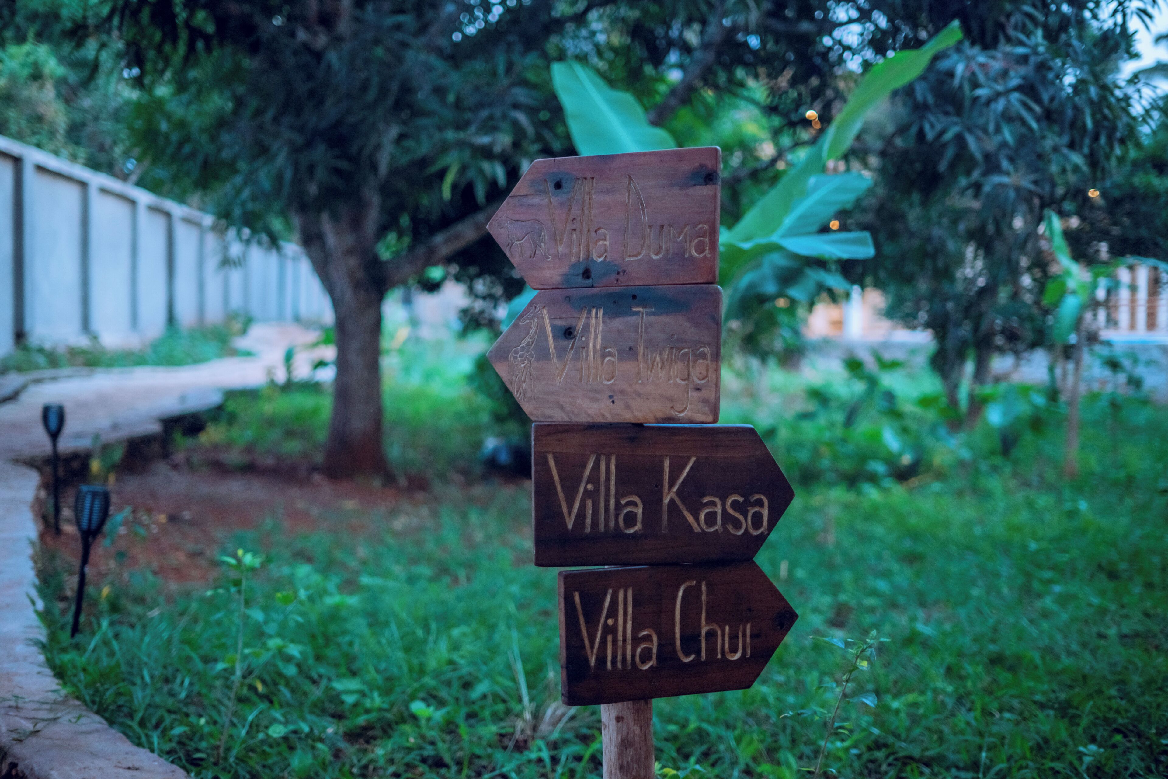 A wooden signpost with directional arrows pointing to different villas.