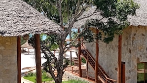 Un edificio tradicional con techo de paja, pared de piedra y escalera de madera que lleva a una puerta.