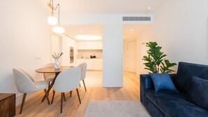 A modern living room with a blue sofa, a dining area with a round table and chairs, and a kitchen in the background. - GuestReady - A peaceful home near downtown (Porto)