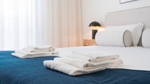 A neatly made bed with folded towels, a bedside lamp, and a framed picture on the wall. - GuestReady - A peaceful home near downtown (Porto)