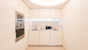 A compact kitchen with white cabinetry, a built-in oven, a sink, and a coffee maker. - GuestReady - A peaceful home near downtown (Porto)